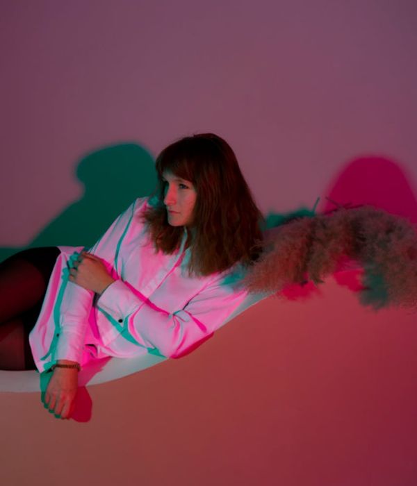 Woman in a calm yoga pose, focusing on breathing, in a dark studio with lime green light.